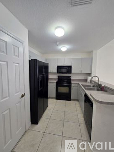 A kitchen with black appliances and white cabinets.