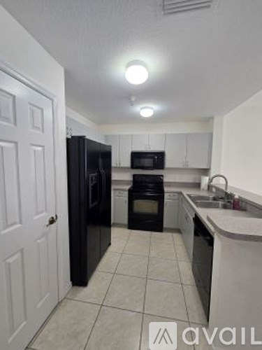 A kitchen with black appliances and white cabinets.
