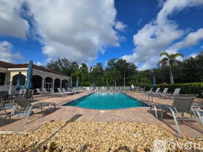 A pool surrounded by chairs and a stone border.