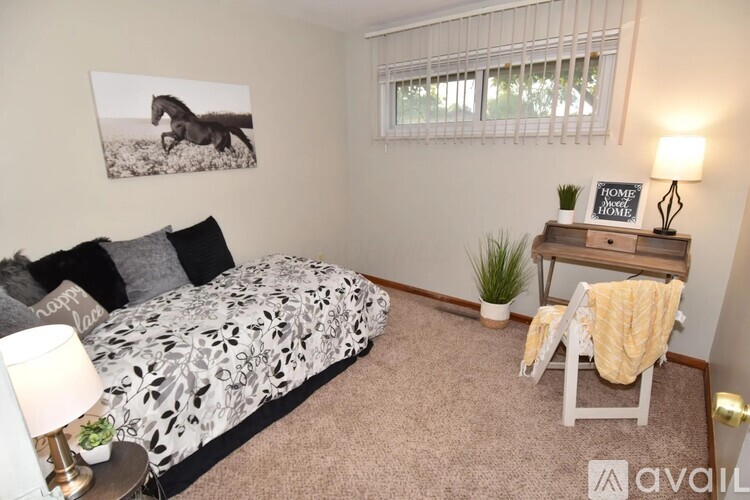 A bedroom with a bed, a desk, and a window.