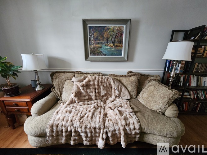 A beige couch with a large blanket on it.