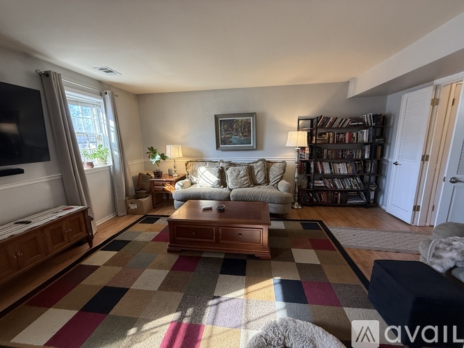 A living room with a checkered rug and a bookshelf.