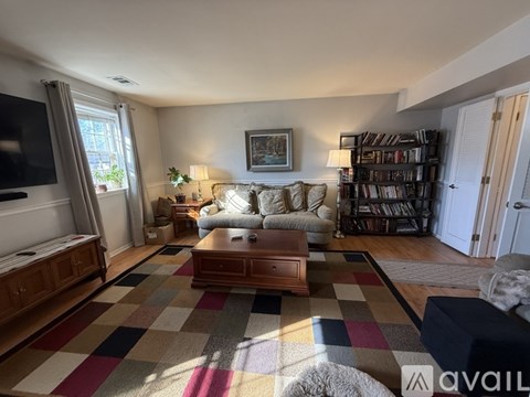 A living room with a checkered rug and a bookshelf.