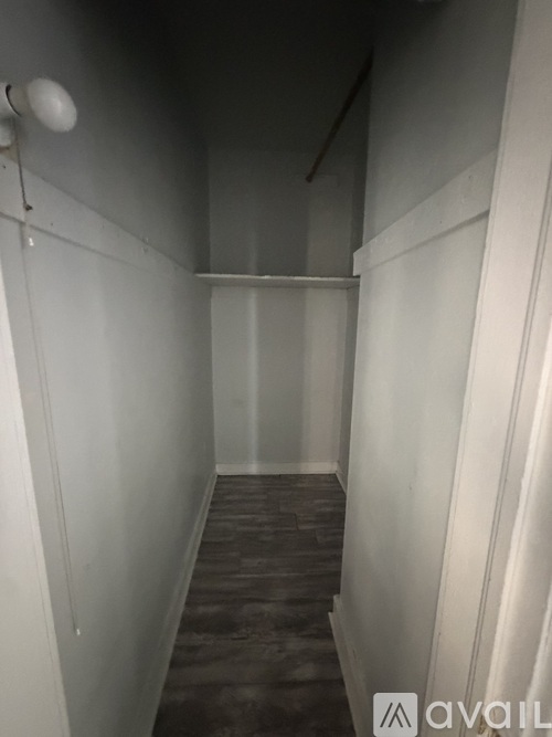 A long, narrow hallway with a light on the left and a sign that says "AVAIL" on the right.