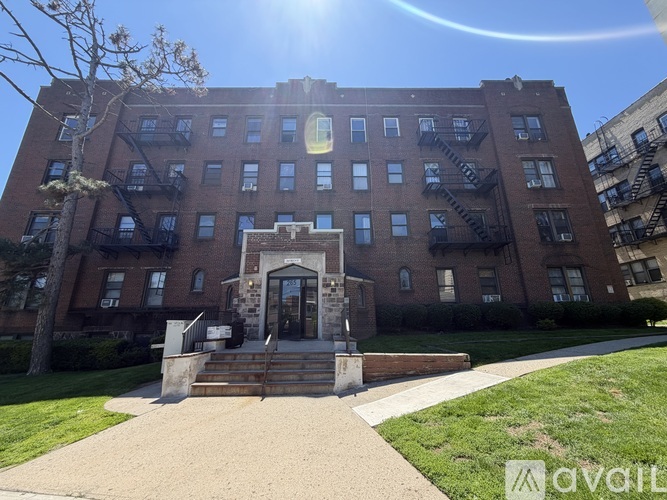 A large brick building with a statue in front and a tree to the left.