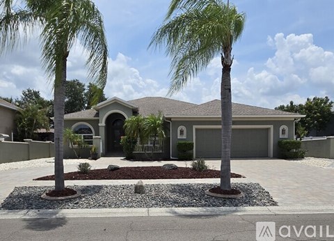 A house with a driveway and two palm trees in front.
