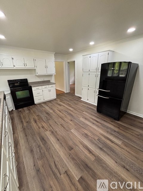A kitchen with a black fridge and wooden floors.
