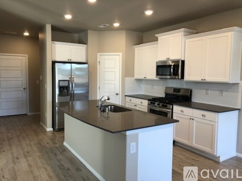 A kitchen with white cabinets and a black countertop.
