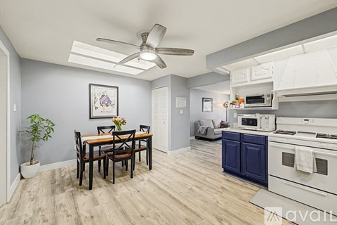 A kitchen with a dining table and chairs in the foreground and a modern kitchen in the background.