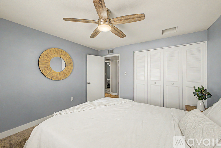A bedroom with a white bed and a ceiling fan.