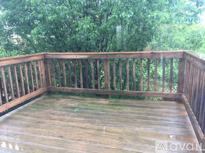 A wooden deck with a railing and trees in the background.