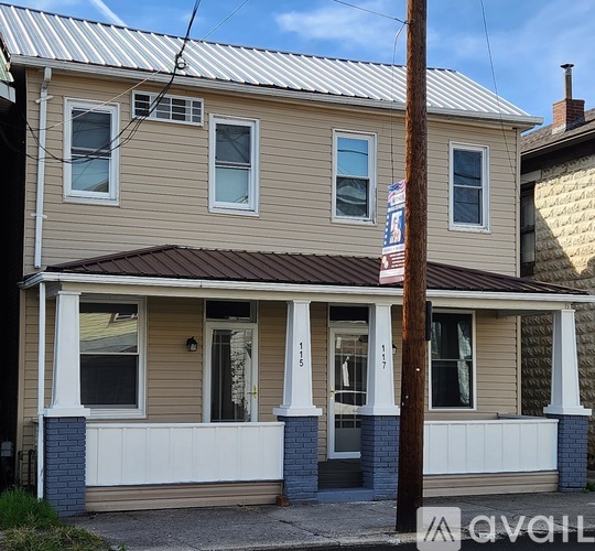 A house with a brown roof and a white porch.