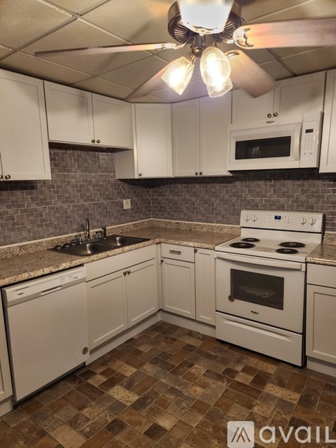 A kitchen with white cabinets and a checkered floor.