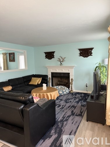 A living room with a black couch and a fireplace.