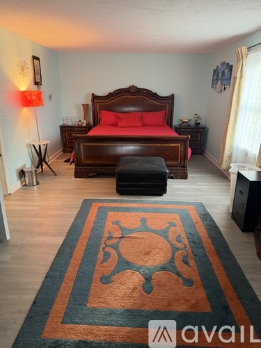 A bedroom with a large bed and a rug on the floor.