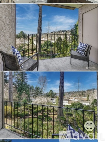 A balcony with a chair and a pillow overlooking a garden.
