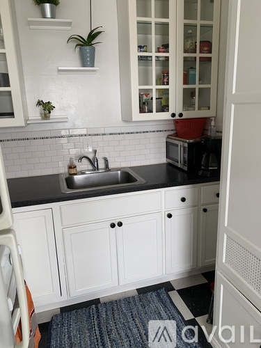 A kitchen with white cabinets and a black countertop.