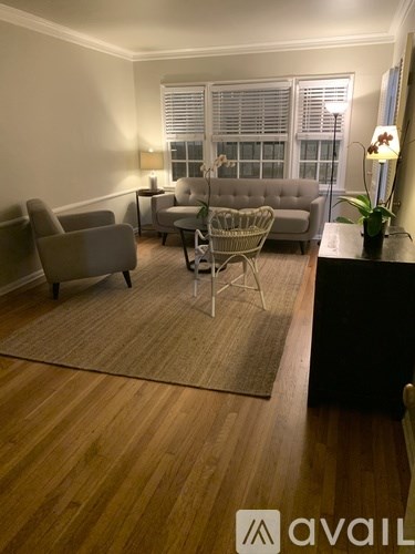 A living room with a grey sofa, two chairs and a rug.