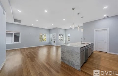 A spacious kitchen with wooden floors and a marble island.