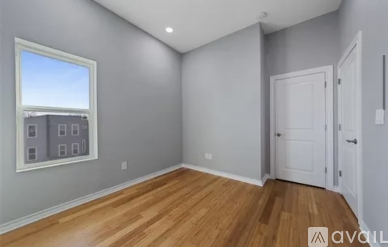 A room with wooden floors and a window overlooking a building.