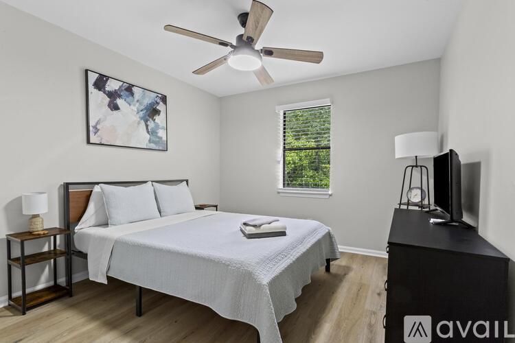 A bedroom with a bed, nightstand, and a painting on the wall.