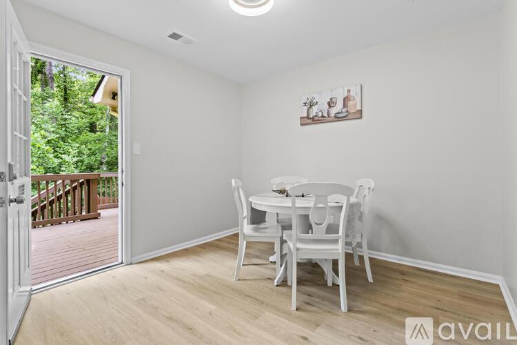A dining room with a white table and chairs and a painting on the wall.