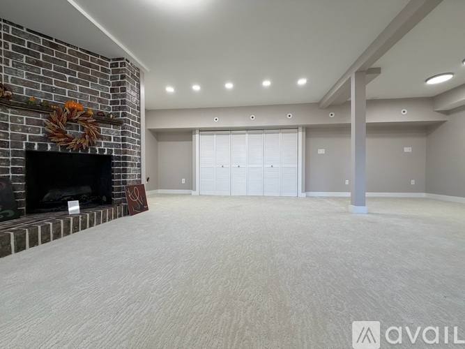 A spacious living room with a fireplace and a wreath on the mantle.