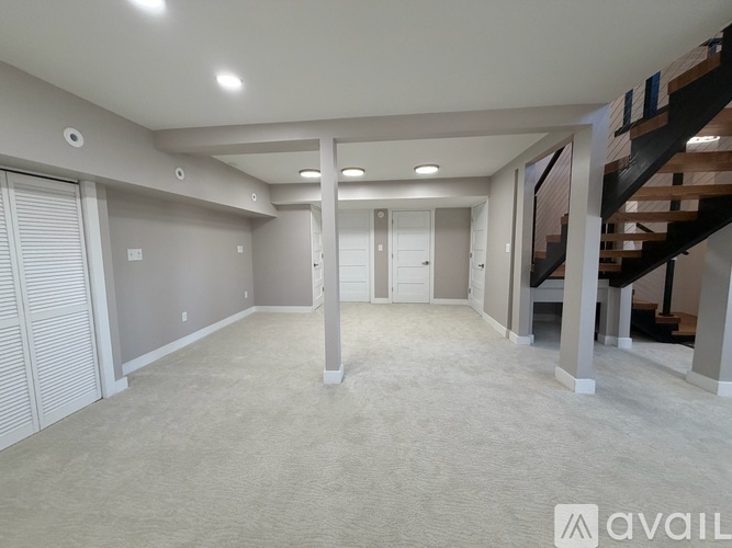 A spacious room with a staircase on the right side.