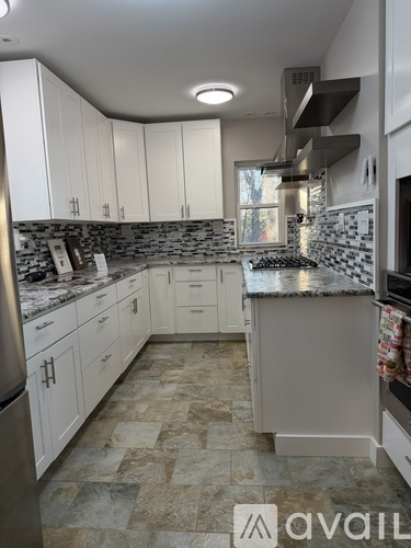 A kitchen with white cabinets and a marble countertop.
