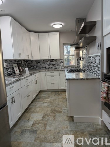 A kitchen with white cabinets and a marble countertop.