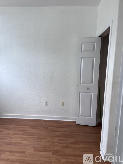 A room with a white door and wooden flooring.