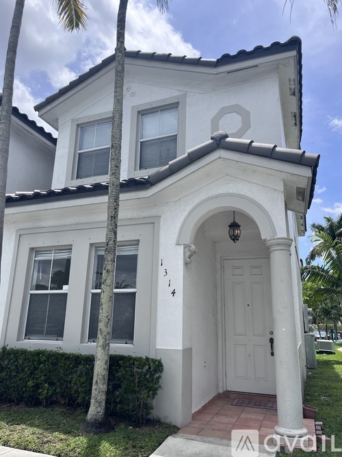 A white house with a black roof and a door with a number 14 on it.