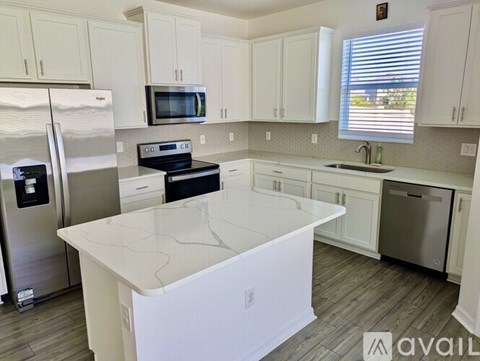A kitchen with white cabinets and a white island.