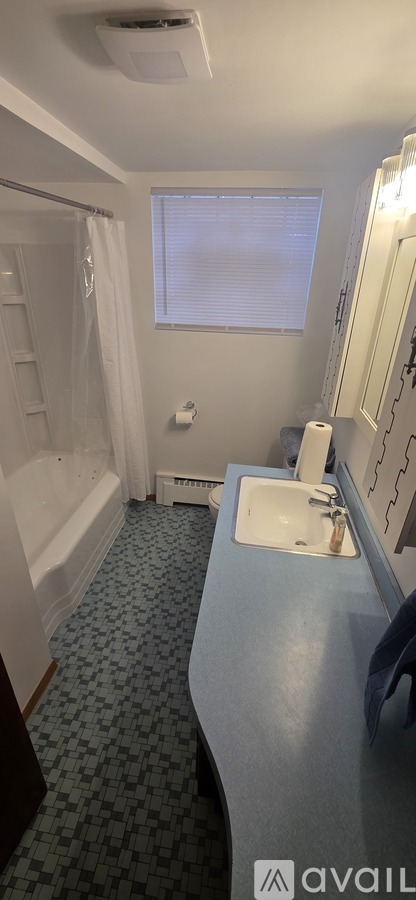 A bathroom with a blue counter and a window with blinds.