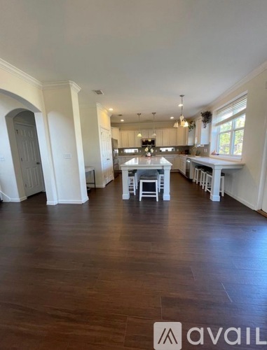 A spacious kitchen and dining area with wooden floors and white walls.