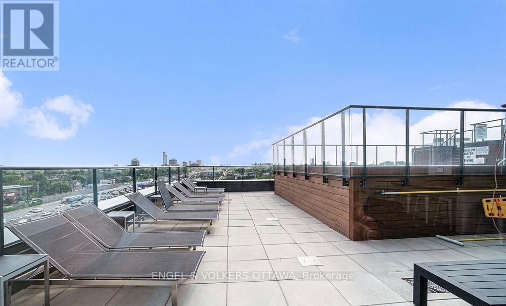 A rooftop patio with a glass railing and wooden decking.