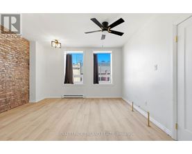 A room with a ceiling fan and a brick wall.