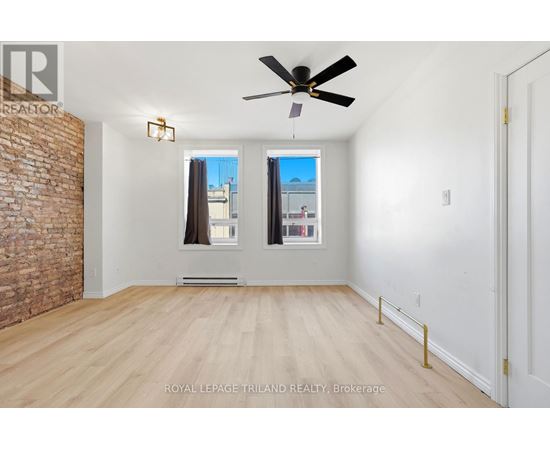 A room with a ceiling fan and a brick wall.
