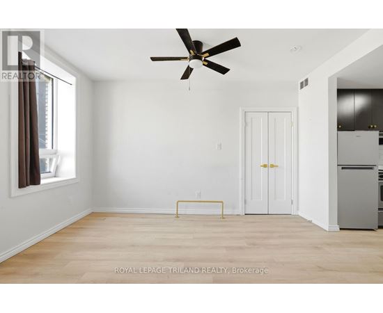 A white room with a ceiling fan and a yellow bench.