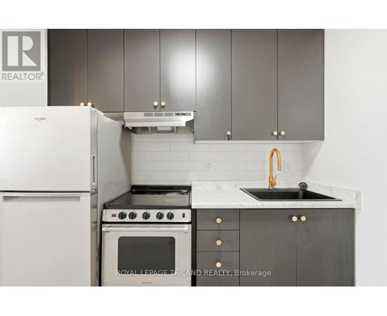 A kitchen with a white fridge, black oven and sink.