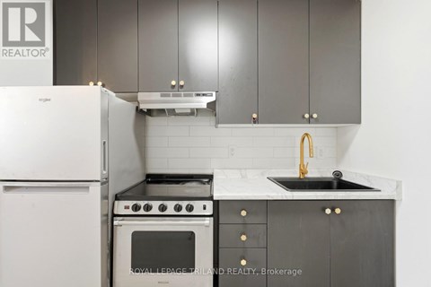 A kitchen with a white fridge, black oven and sink.