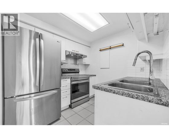 A modern kitchen with a stainless steel refrigerator and granite countertop.