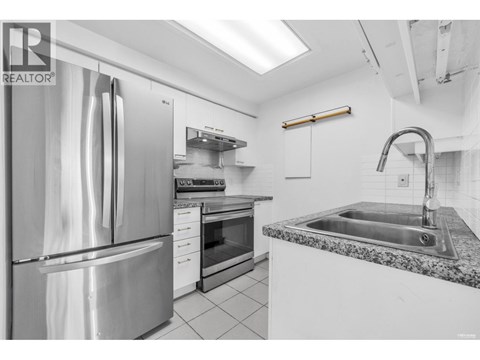 A modern kitchen with a stainless steel refrigerator and granite countertop.