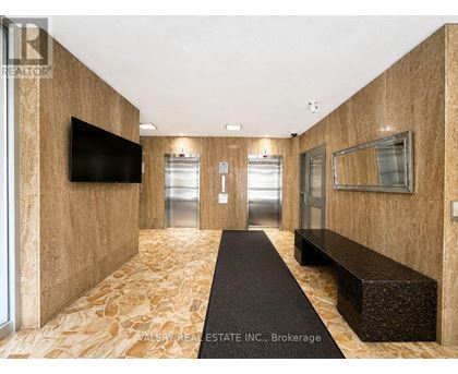 A hallway with a bench and a television on the wall.