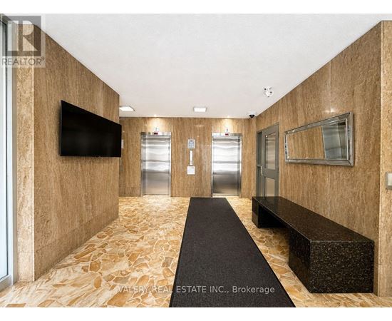 A hallway with a bench and a television on the wall.