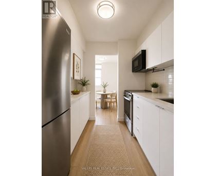 A kitchen with white cabinets and a stainless steel refrigerator.