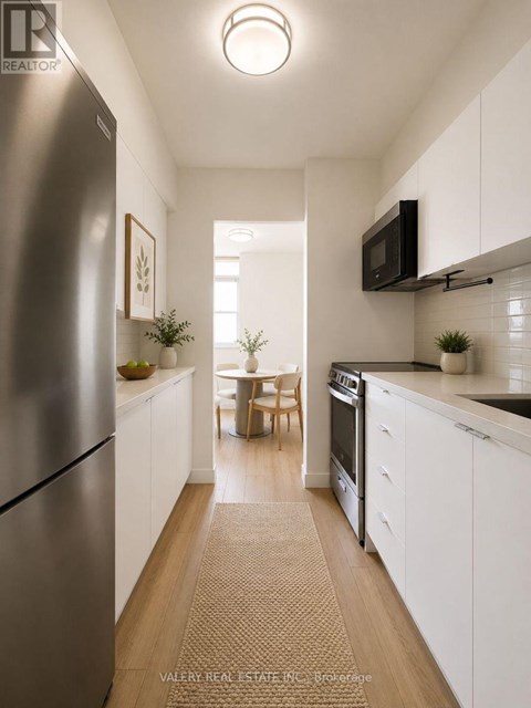 A kitchen with white cabinets and a stainless steel refrigerator.
