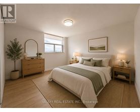 A bedroom with a bed, nightstand, and a plant.