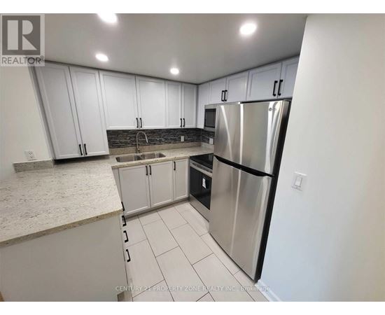 A kitchen with white cabinets and a stainless steel refrigerator.