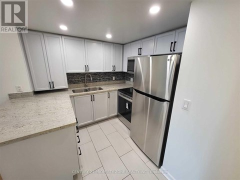 A kitchen with white cabinets and a stainless steel refrigerator.